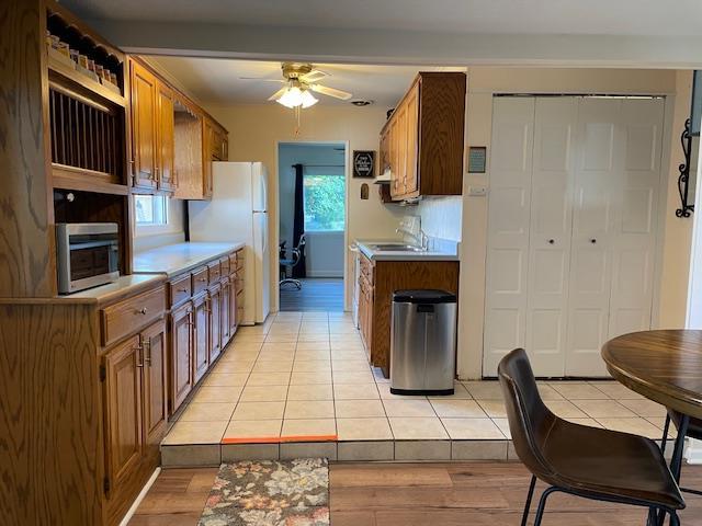 212 E N St, Benton, MO 63736 - kitchen with freestanding refrigerator, a ceiling fan, stainless steel microwave, and brown cabinetry