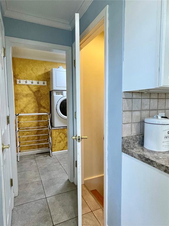 17250 Brewster Ln, Crocker, MO 65452 - bathroom with stacked washer / drying machine, crown molding, tile patterned floors, and decorative backsplash