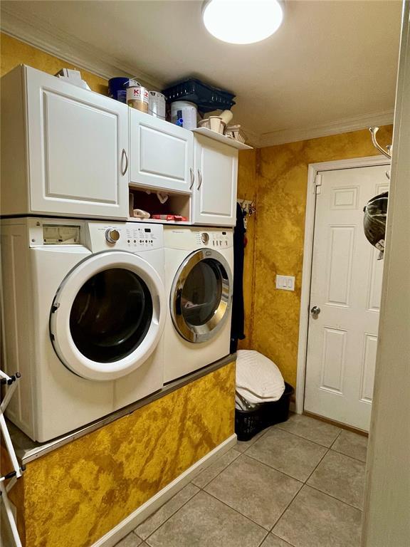 17250 Brewster Ln, Crocker, MO 65452 - laundry area with cabinet space, washer and clothes dryer, ornamental molding, and light tile patterned floors