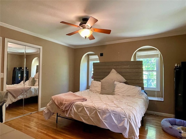 17250 Brewster Ln, Crocker, MO 65452 - bedroom featuring arched walkways, wood finished floors, baseboards, a closet, and ceiling fan