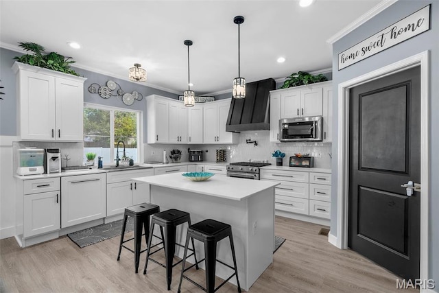 28 Millwell Dr, Maryland Heights, MO 63043 - kitchen with stainless steel appliances, crown molding, wall chimney exhaust hood, a breakfast bar area, and light countertops