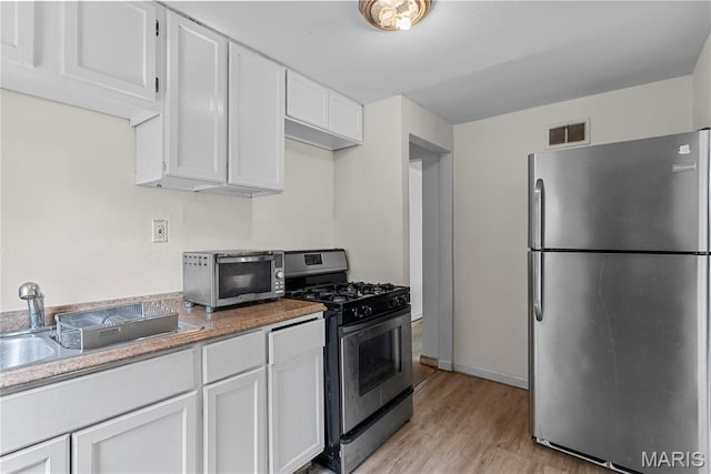 1937 N Hanley Rd, Saint Louis, MO 63114 - kitchen with stainless steel appliances, light wood-type flooring, and white cabinetry