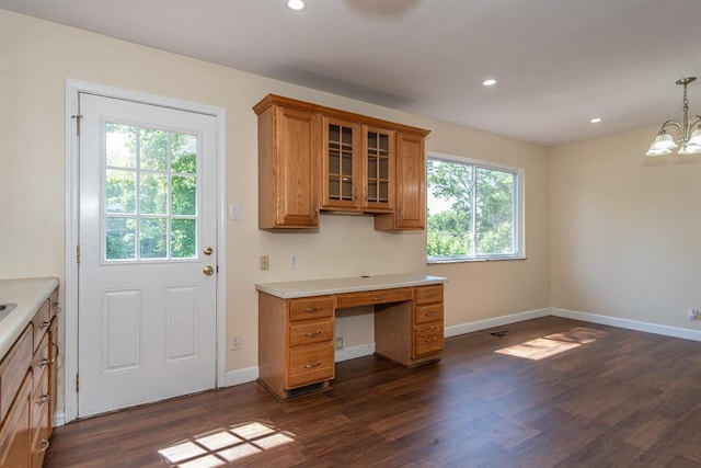 505 Stephanie Ln, Manchester, MO 63011 - kitchen with brown cabinetry, dark wood-style flooring, light countertops, a chandelier, and glass insert cabinets