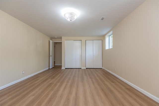 505 Stephanie Ln, Manchester, MO 63011 - unfurnished bedroom with multiple closets, baseboards, and light wood-style flooring
