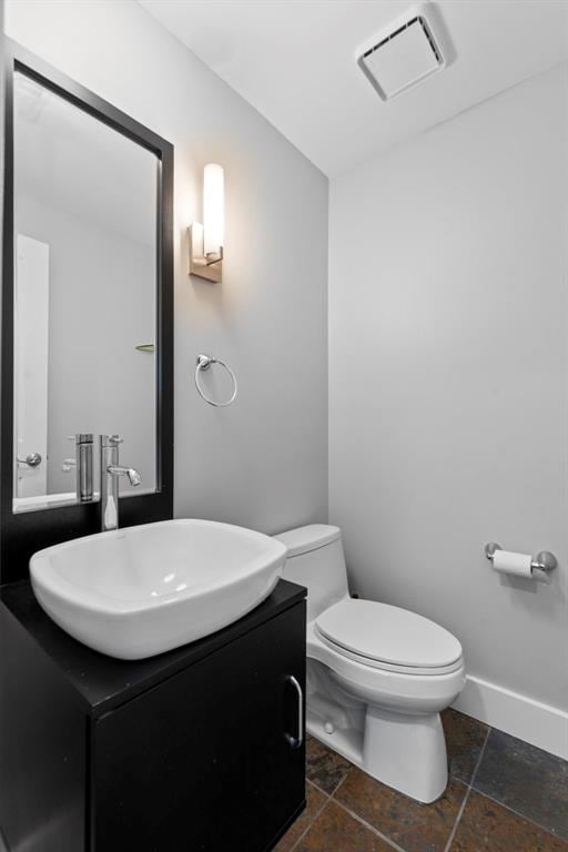 603 Westgate Ave Unit 603E, Saint Louis, MO 63130 - half bath with vanity, toilet, stone tile floors, and baseboards