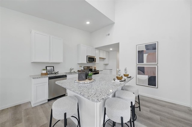 4001 Marais Temps Clair Dr, Saint Charles, MO 63304 - kitchen featuring appliances with stainless steel finishes, a kitchen breakfast bar, light wood-style floors, white cabinets, and recessed lighting