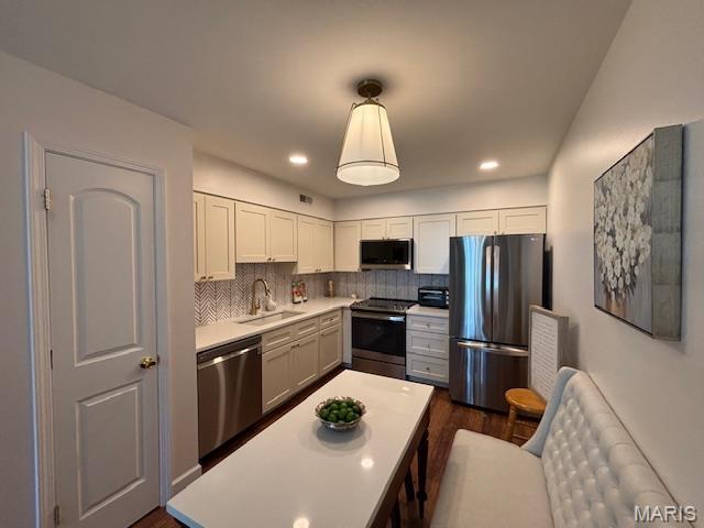 9608 Bent Pine Dr H, Unit H, MO 63126 - kitchen featuring stainless steel appliances, a sink, light countertops, tasteful backsplash, and dark wood-style flooring