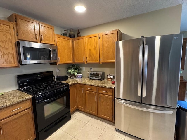 113 Fairway Dr, Maryville, IL 62062 - kitchen featuring stainless steel appliances, light tile patterned floors, brown cabinets, light stone countertops, and a textured ceiling