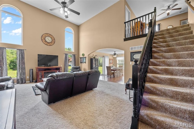 8525 Sagamore Dr, Cedar Hill, MO 63016 - carpeted living area featuring a ceiling fan, high vaulted ceiling, arched walkways, stairs, and plenty of natural light