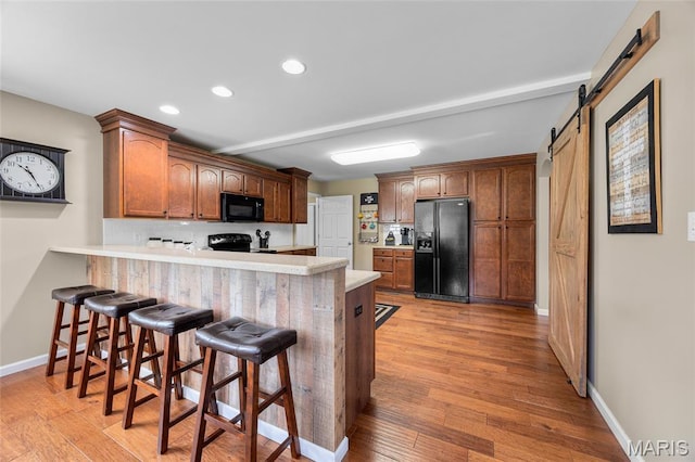 8525 Sagamore Dr, Cedar Hill, MO 63016 - kitchen featuring black appliances, recessed lighting, a barn door, light countertops, and light wood finished floors