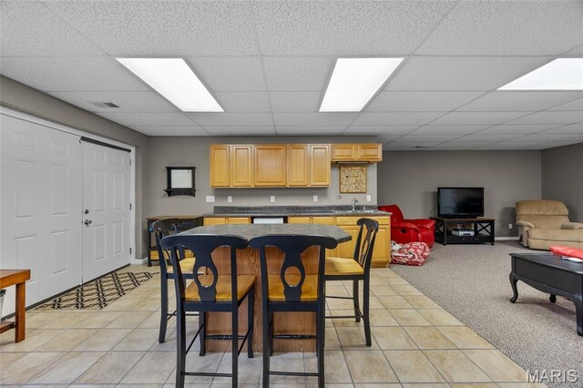 8525 Sagamore Dr, Cedar Hill, MO 63016 - kitchen featuring light brown cabinetry, a paneled ceiling, dark countertops, light tile patterned floors, and light colored carpet