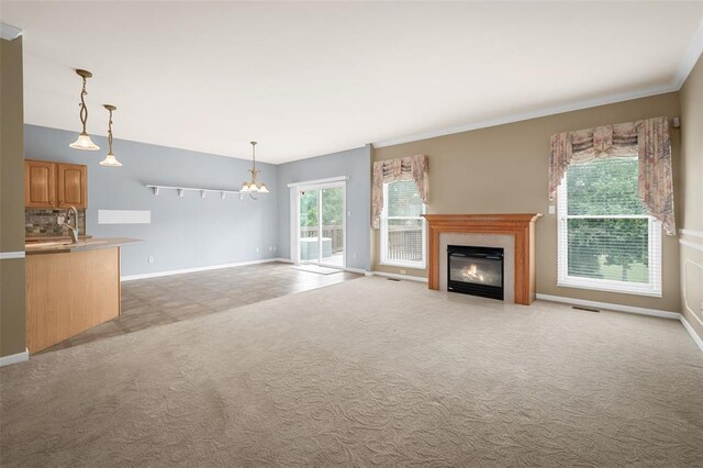 734 River Glen Dr, Ofallon, MO 63368 - unfurnished living room featuring baseboards, a fireplace, crown molding, a sink, and light carpet