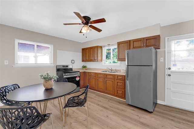 655 5th Plz, Florissant, MO 63031 - kitchen featuring appliances with stainless steel finishes, a sink, brown cabinets, and light wood-style floors