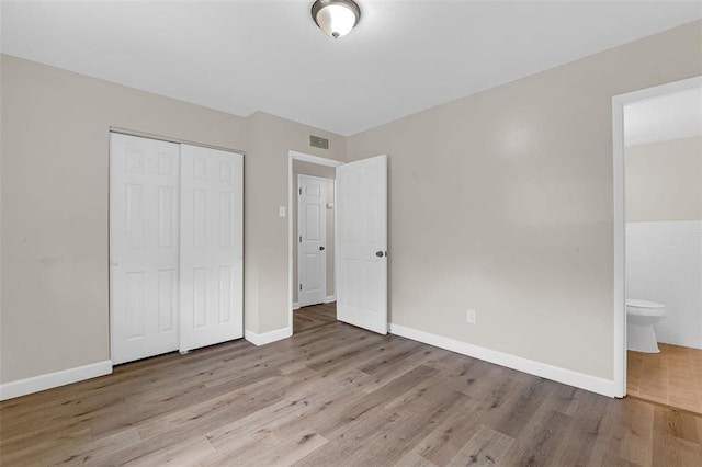 655 5th Plz, Florissant, MO 63031 - unfurnished bedroom with wood finished floors, a closet, baseboards, and ensuite bath