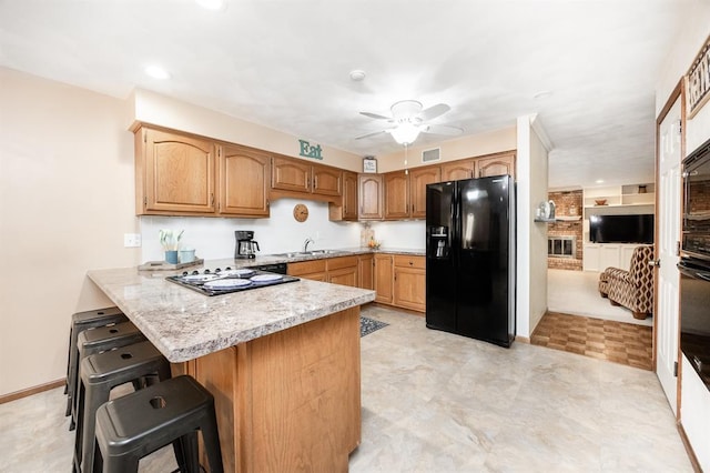 14 Shallowbrook Dr, Ofallon, IL 62269 - kitchen featuring black fridge, a peninsula, a sink, a kitchen breakfast bar, and ceiling fan
