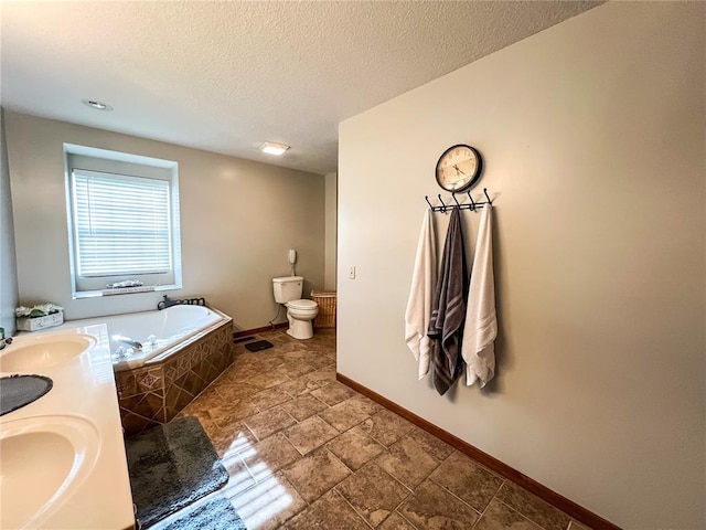 619 Cleveland St, Paris, MO 65275 - bathroom with toilet, a bath, baseboards, a textured ceiling, and double vanity