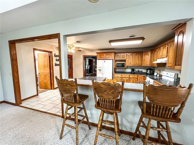 619 Cleveland St, Paris, MO 65275 - kitchen with electric stove, white refrigerator with ice dispenser, under cabinet range hood, a peninsula, and brown cabinets