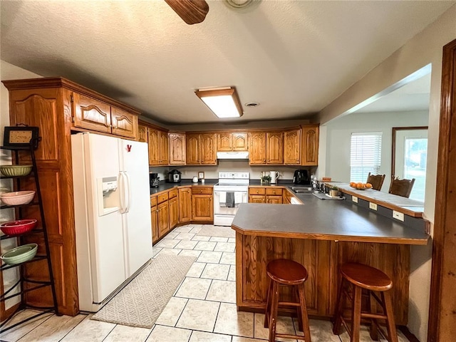 619 Cleveland St, Paris, MO 65275 - kitchen featuring white appliances, under cabinet range hood, brown cabinetry, and a peninsula