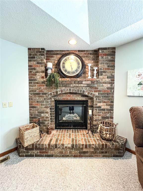 619 Cleveland St, Paris, MO 65275 - detailed view of carpet flooring, a textured ceiling, a fireplace, and baseboards