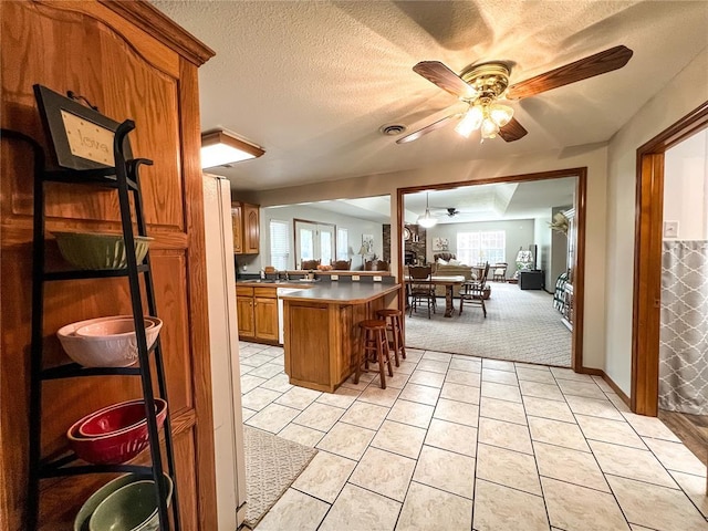 619 Cleveland St, Paris, MO 65275 - kitchen with a ceiling fan, open floor plan, brown cabinetry, a kitchen bar, and light tile patterned flooring