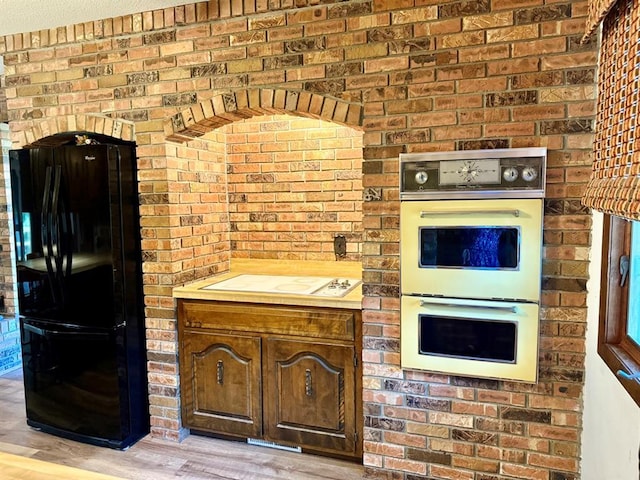 16463 Terrace Dr, Dexter, MO 63841 - kitchen with white appliances, light wood finished floors, and brick wall