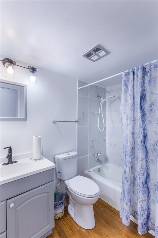 6691 Parker Rd Unit A, Florissant, MO 63033 - bathroom with vanity, toilet, wood finished floors, and shower / bath combination with curtain