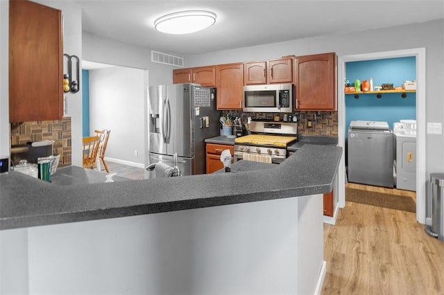 1519 Progress Ln, Belleville, IL 62221 - kitchen featuring stainless steel appliances, separate washer and dryer, light wood-type flooring, backsplash, and dark countertops