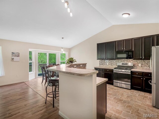 1109 Foxwood Estates Dr, Arnold, MO 63010 - kitchen featuring stainless steel appliances, vaulted ceiling, backsplash, light countertops, and a kitchen bar