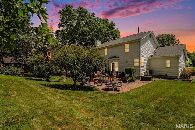 1575 Uthoff Dr, Fenton, MO 63026 - back of property at dusk with a patio area, a lawn, and a chimney