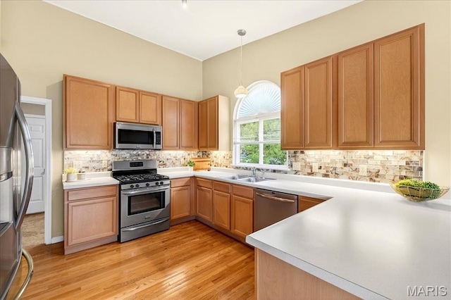 1423 Villas Estates Dr, Saint Louis, MO 63026 - kitchen featuring stainless steel appliances, light wood finished floors, decorative light fixtures, and tasteful backsplash