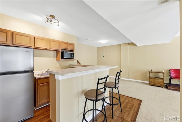 1423 Villas Estates Dr, Saint Louis, MO 63026 - kitchen with stainless steel appliances, a breakfast bar area, light countertops, and dark carpet