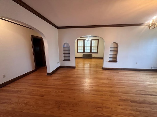 417 S Kingshighway St, Sikeston, MO 63801 - unfurnished living room featuring arched walkways, built in shelves, ornamental molding, radiator, and a chandelier