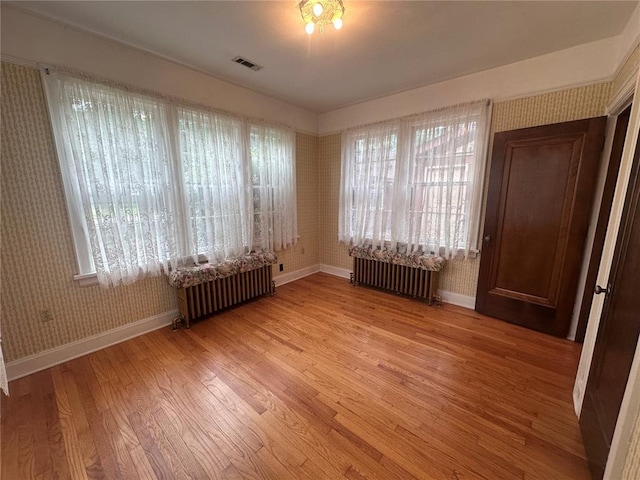 417 S Kingshighway St, Sikeston, MO 63801 - empty room with radiator heating unit, baseboards, light wood-style floors, wallpapered walls, and healthy amount of natural light