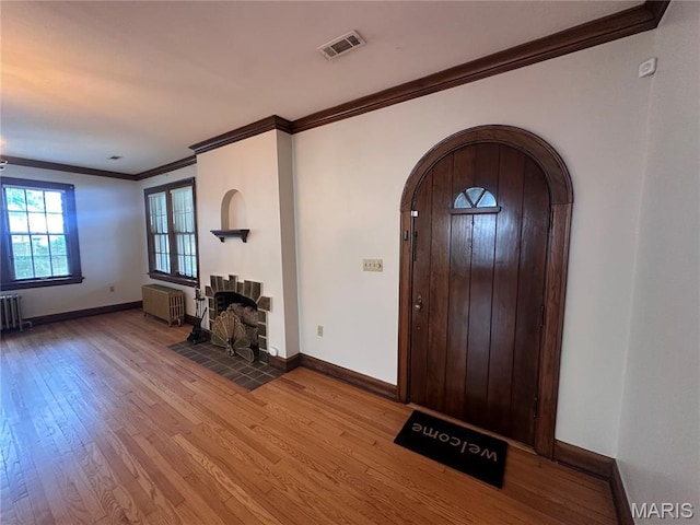 417 S Kingshighway St, Sikeston, MO 63801 - foyer with arched walkways, radiator, crown molding, wood finished floors, and radiator heating unit