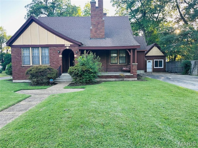 417 S Kingshighway St, Sikeston, MO 63801 - english style home with brick siding, a chimney, a shingled roof, board and batten siding, and covered porch