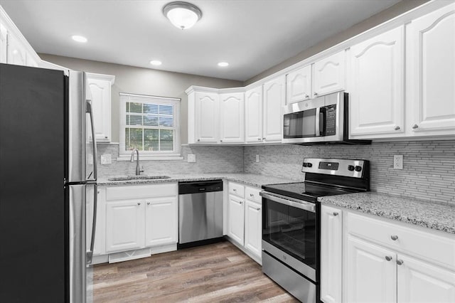 113 Brand Ave, Red Bud, IL 62278 - kitchen with appliances with stainless steel finishes, a sink, white cabinetry, light wood-style flooring, and decorative backsplash