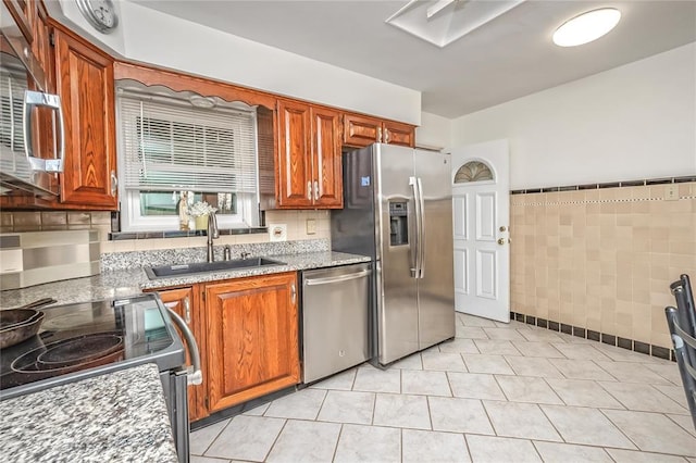 12810 Big Bend Rd, Kirkwood, MO 63122 - kitchen featuring appliances with stainless steel finishes, tile walls, a sink, wainscoting, and brown cabinets
