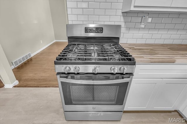 3368 S Suncrest Ave, Saint Louis, MO 63114 - kitchen featuring gas stove, butcher block counters, white cabinets, and tasteful backsplash
