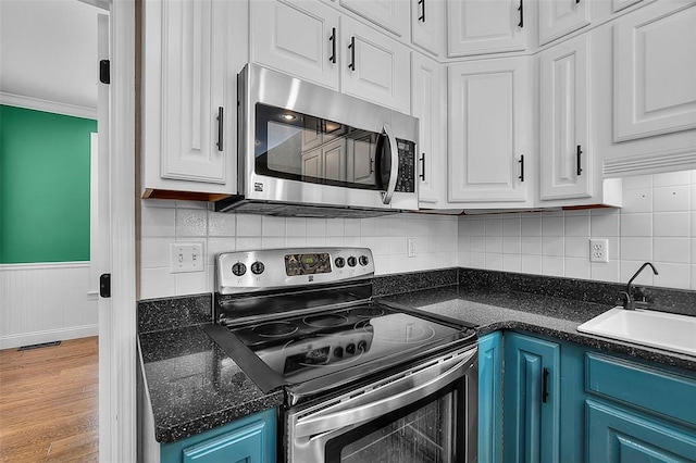1014 Trailridge Dr, Jackson, MO 63755 - kitchen with stainless steel appliances, a sink, white cabinetry, blue cabinets, and wainscoting