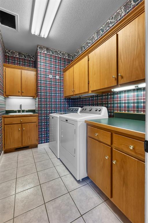 1014 Trailridge Dr, Jackson, MO 63755 - washroom with cabinet space, wallpapered walls, independent washer and dryer, a textured ceiling, and light tile patterned floors