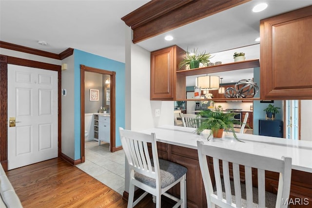 2854 Championship Blvd, Saint Louis, MO 63129 - kitchen featuring light countertops, open shelves, brown cabinetry, light wood finished floors, and a kitchen breakfast bar