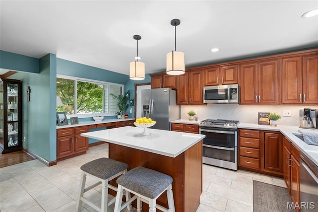 2854 Championship Blvd, Saint Louis, MO 63129 - kitchen with appliances with stainless steel finishes, light countertops, a breakfast bar, brown cabinetry, and recessed lighting
