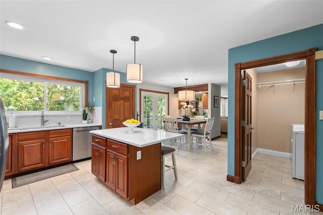 2854 Championship Blvd, Saint Louis, MO 63129 - kitchen featuring a sink, dishwasher, light countertops, brown cabinetry, and a kitchen breakfast bar
