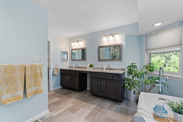 2854 Championship Blvd, Saint Louis, MO 63129 - full bathroom with double vanity, a soaking tub, wood finished floors, and baseboards