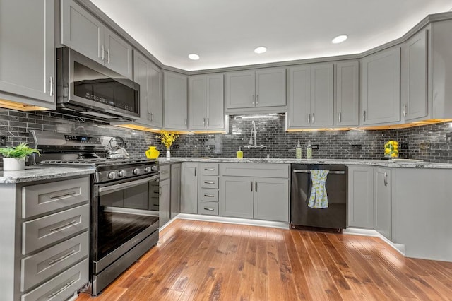 1354 Nutmeg Dr, Saint Charles, MO 63303 - kitchen featuring appliances with stainless steel finishes, gray cabinetry, light wood-style floors, decorative backsplash, and recessed lighting