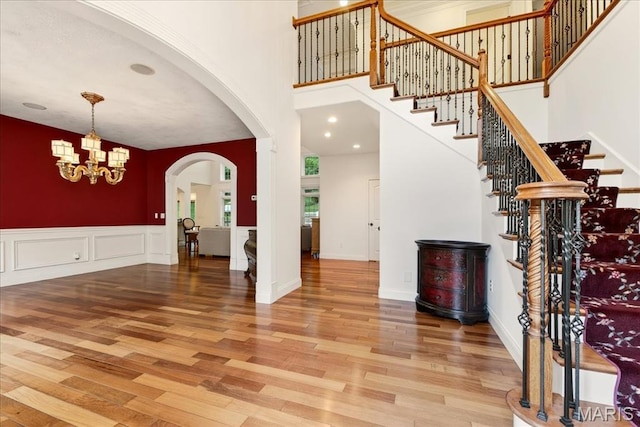 125 Park Lawn Est, Fenton, MO 63026 - foyer with wood finished floors, a chandelier, stairs, arched walkways, and a towering ceiling