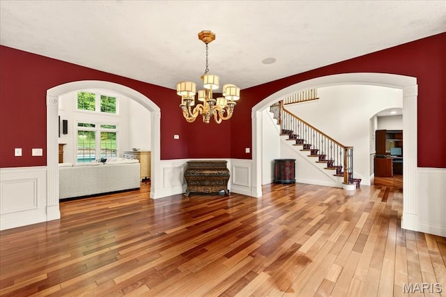125 Park Lawn Est, Fenton, MO 63026 - unfurnished living room with stairway, wainscoting, hardwood / wood-style flooring, arched walkways, and a chandelier