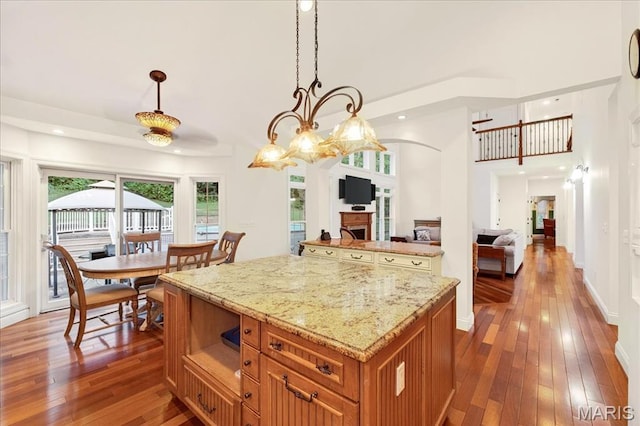 125 Park Lawn Est, Fenton, MO 63026 - kitchen featuring dark wood-style floors, a center island, brown cabinets, light stone countertops, and healthy amount of natural light