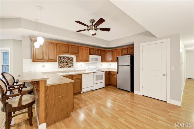 125 Park Lawn Est, Fenton, MO 63026 - kitchen with white appliances, a peninsula, light wood-type flooring, a breakfast bar, and light countertops