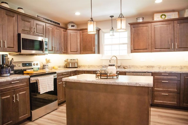 20083 Southview Dr, Carlyle, IL 62231 - kitchen with stainless steel appliances, light wood-style floors, a sink, a kitchen island, and hanging light fixtures